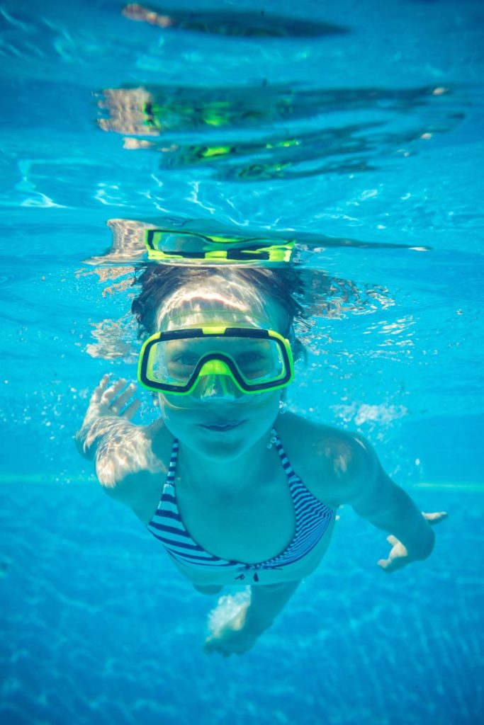 Una giovane nuotatrice sott’acqua con maschera verde